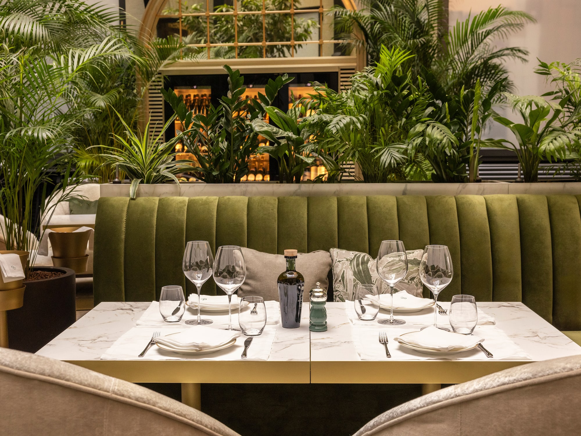 a table set for a dinner with a green couch and plants