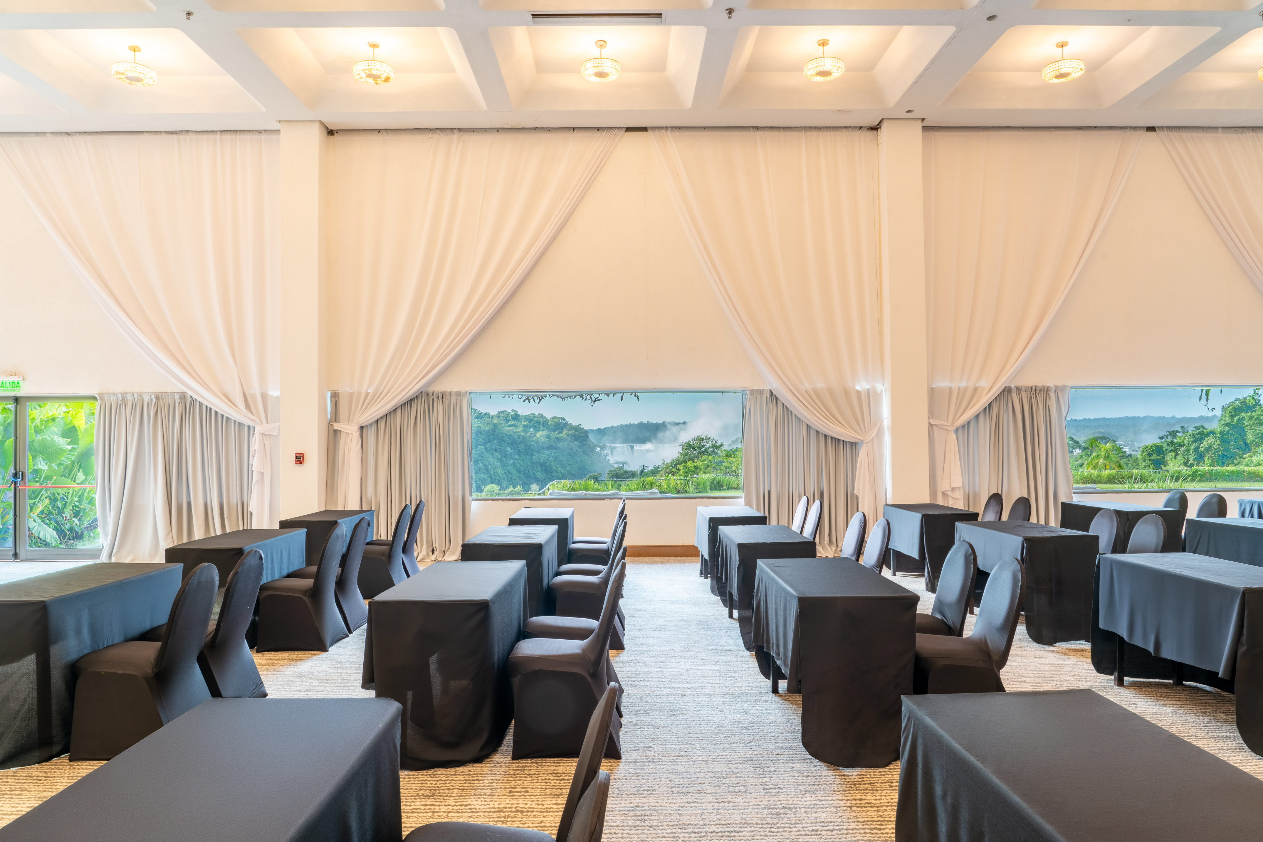 Conference room with black tables, chairs, and waterfall view.
