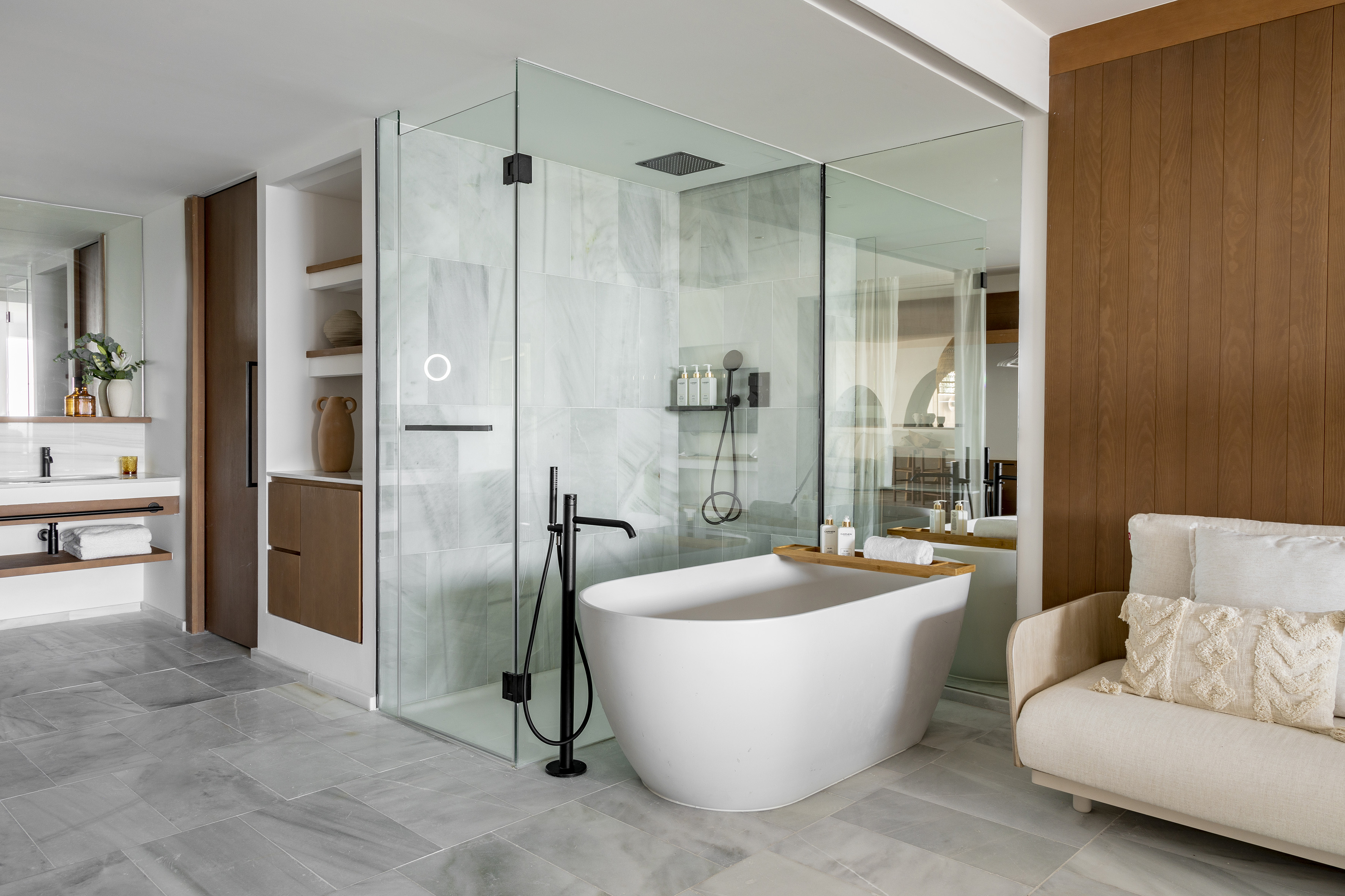 Luxury spa bathroom with freestanding tub, glass shower, marble, and wood.