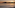 Serene sunset over ocean with paddleboarder, mountains, and gentle waves.