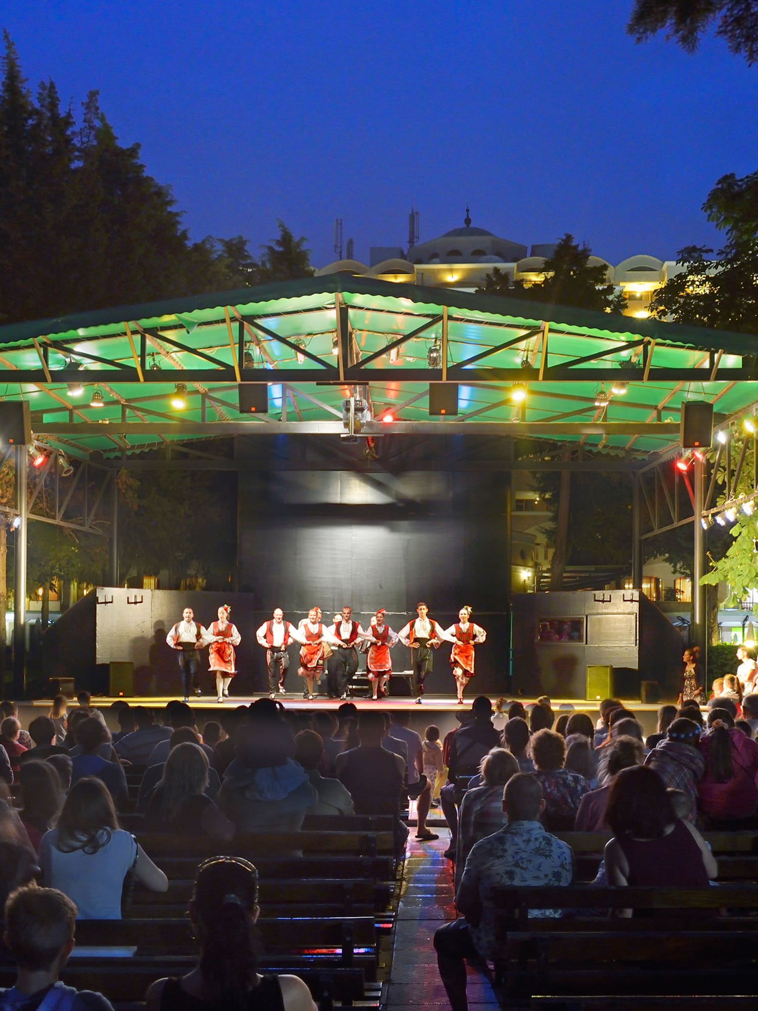 a group of people on a stage with Greek Theatre in the background