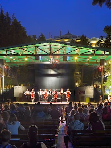 a group of people on a stage with Greek Theatre in the background