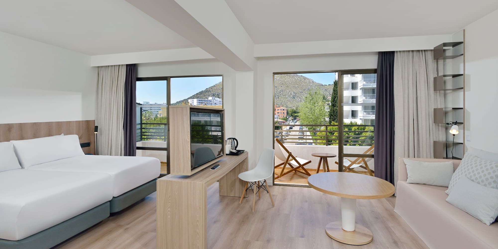 Spacious hotel room with mountain view balcony, twin beds, and modern decor.