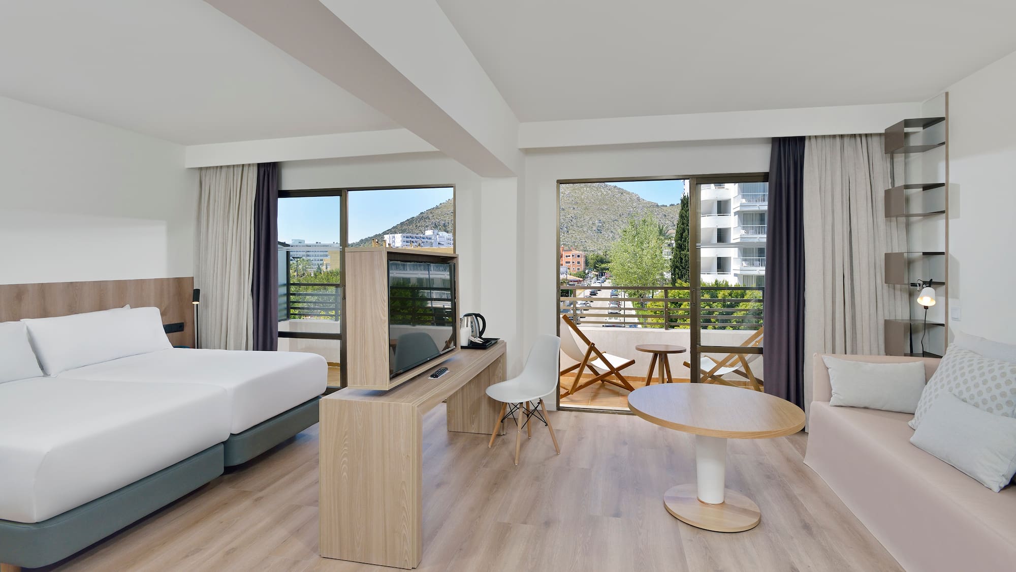 Spacious hotel room with mountain view balcony, twin beds, and modern decor.