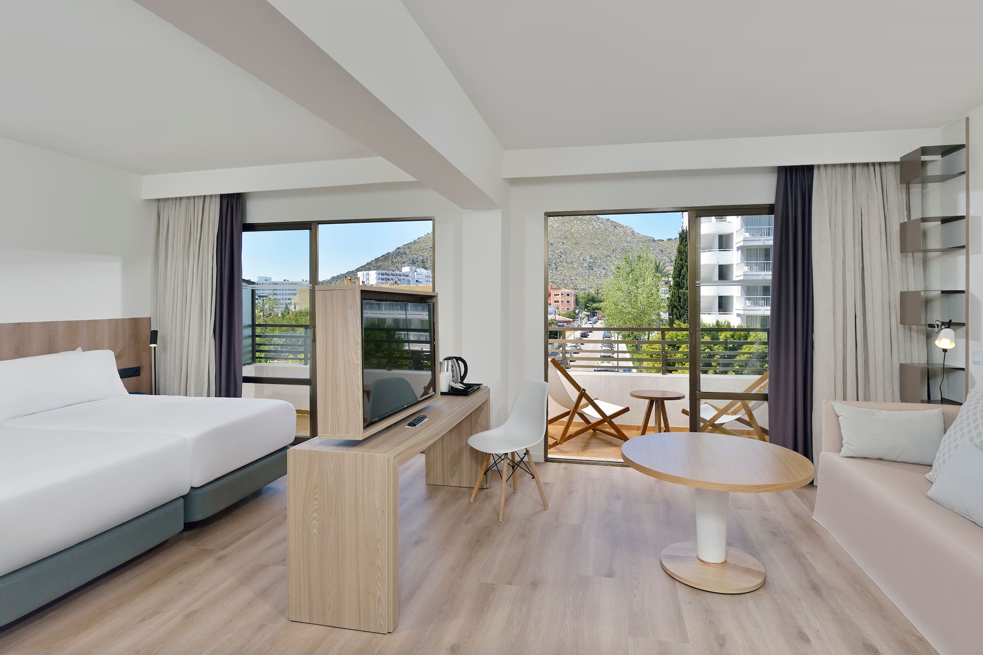 Spacious hotel room with mountain view balcony, twin beds, and modern decor.