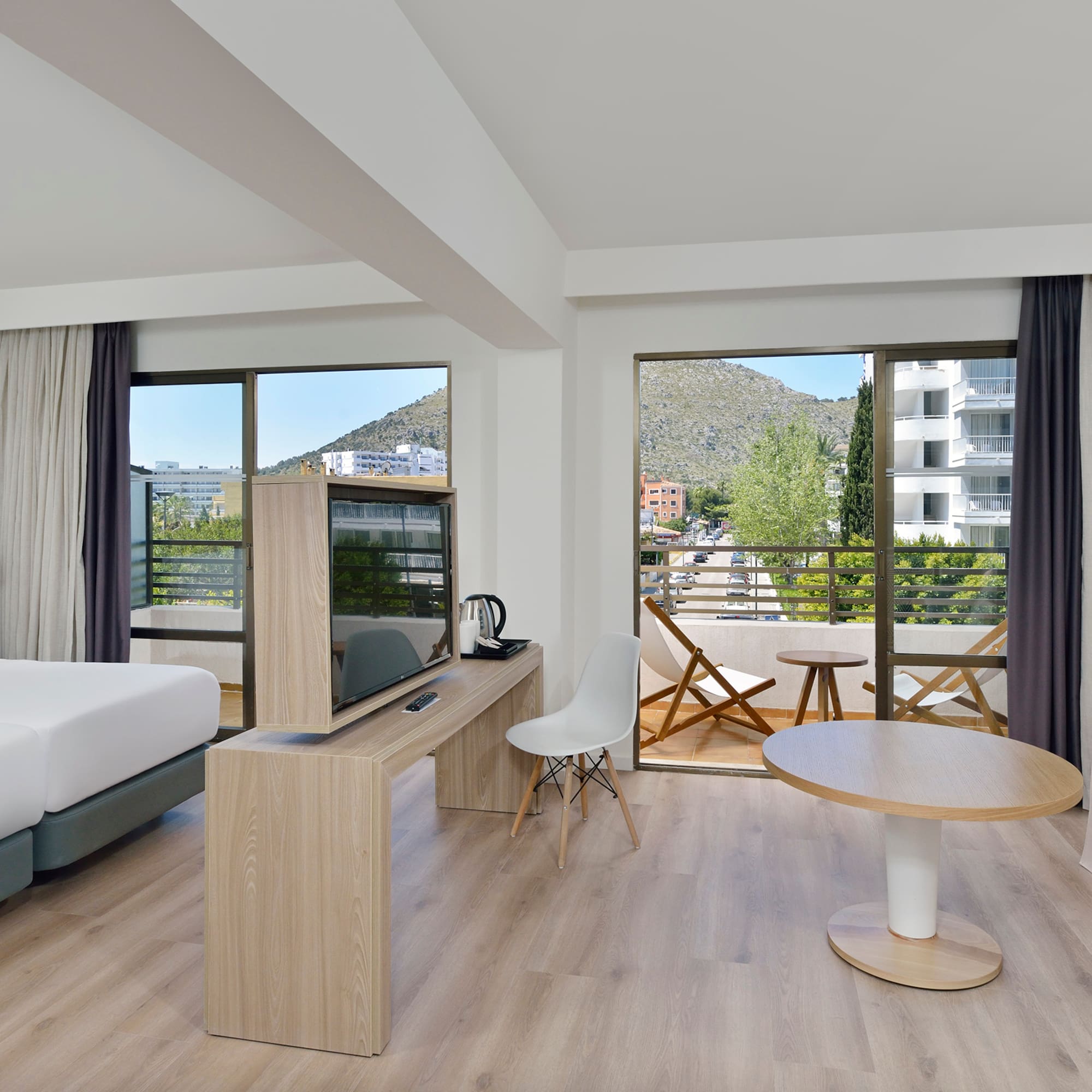 Spacious hotel room with mountain view balcony, twin beds, and modern decor.