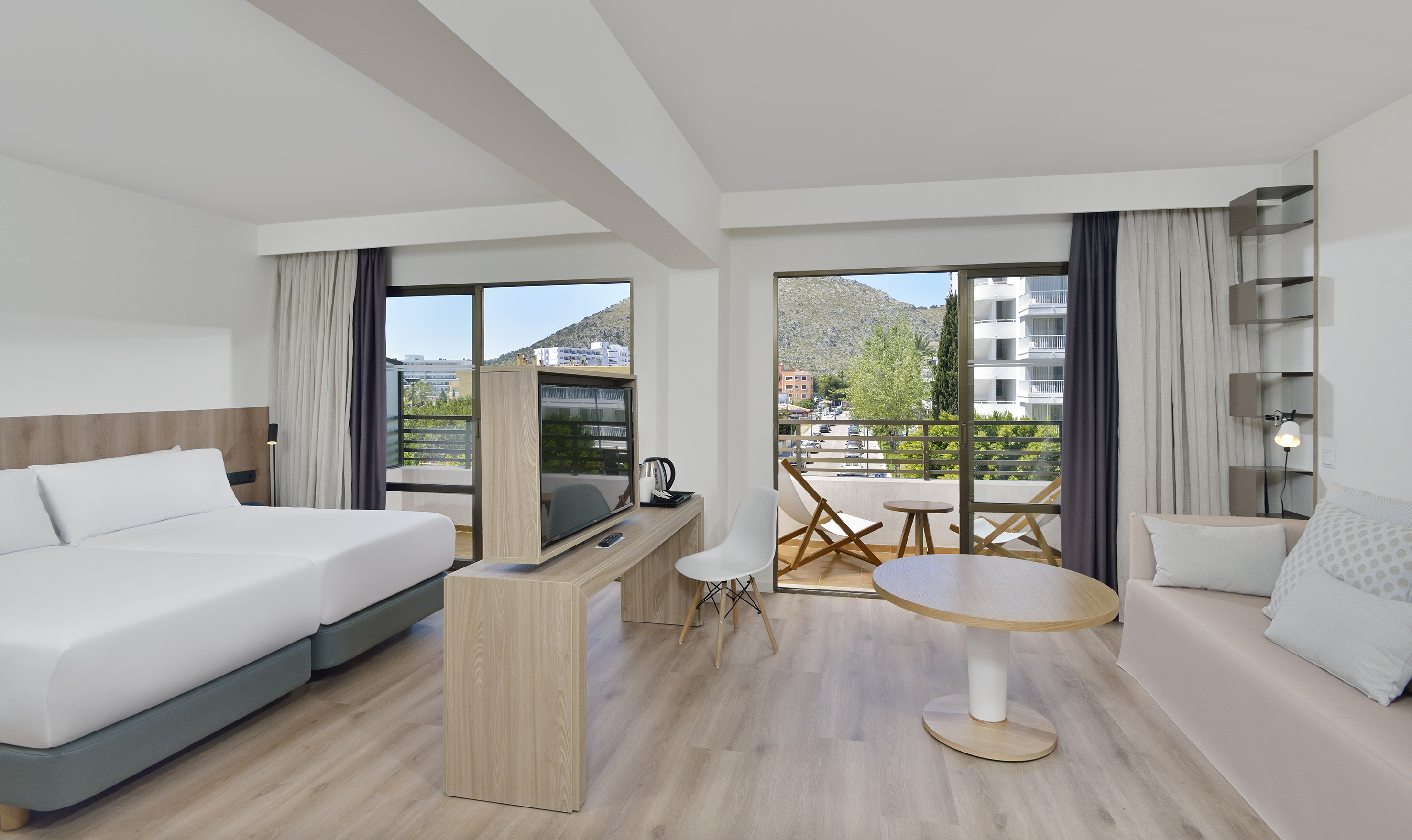 Spacious hotel room with mountain view balcony, twin beds, and modern decor.
