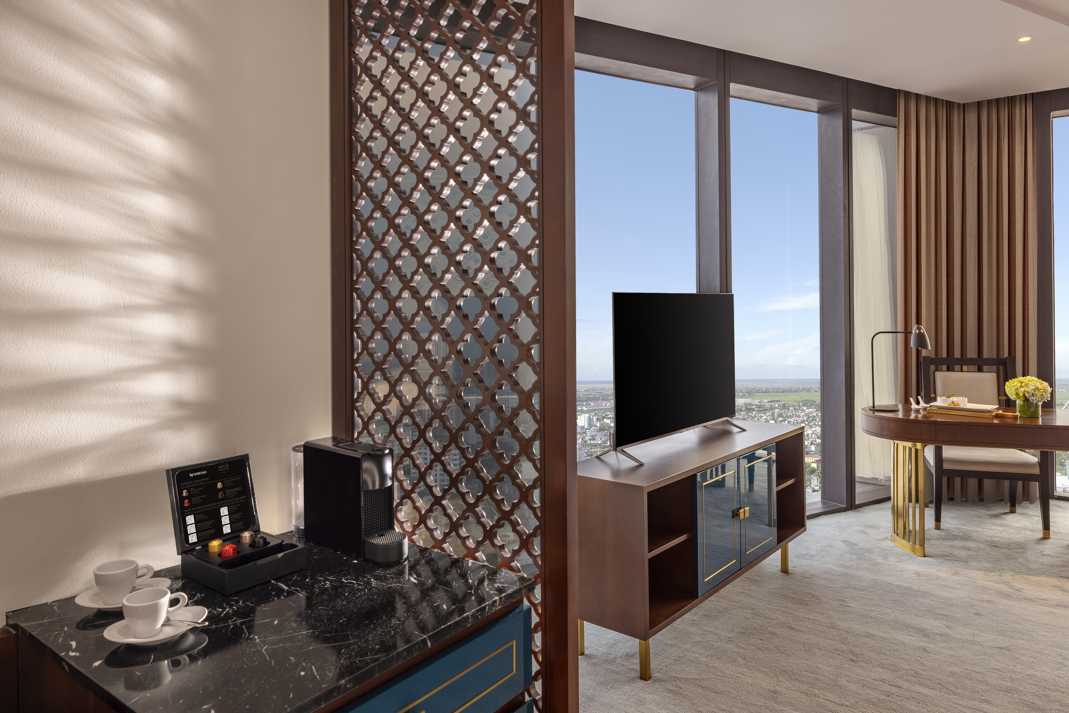 Modern hotel suite with Nespresso machine, city view, and elegant room divider.