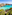 Clear turquoise bay, rocky shoreline, green shrubs, and distant boats.