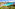 Clear turquoise bay, rocky shoreline, green shrubs, and distant boats.