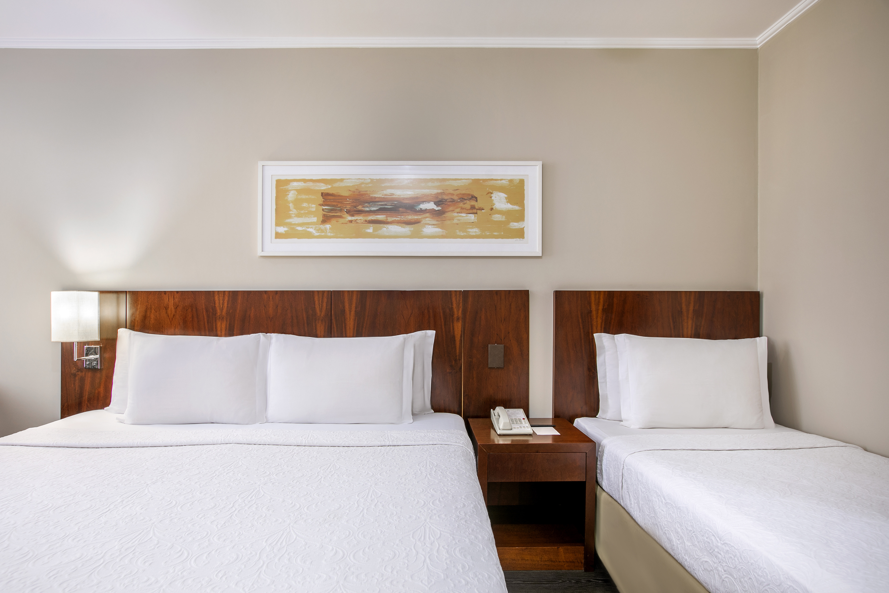 Modern hotel guest room with queen and twin beds, crisp white bedding.