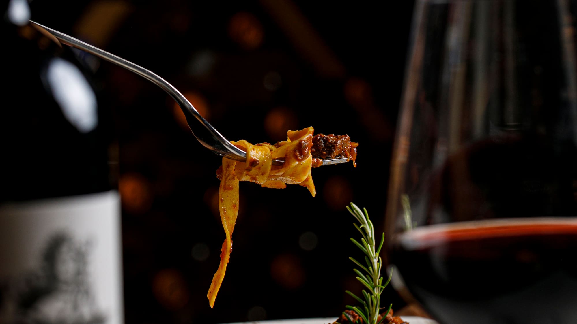 a fork on a plate of pasta and a glass of wine