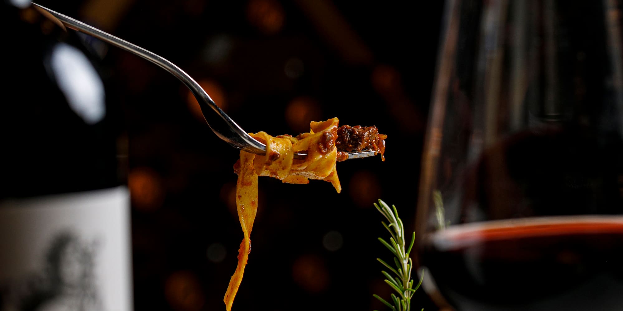 a fork on a plate of pasta and a glass of wine
