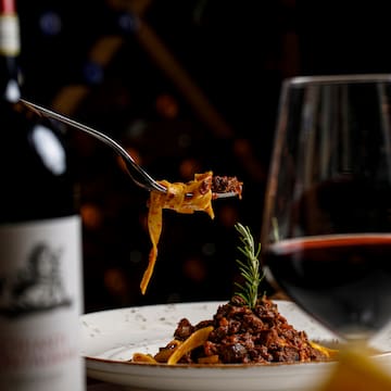a fork on a plate of pasta and a glass of wine
