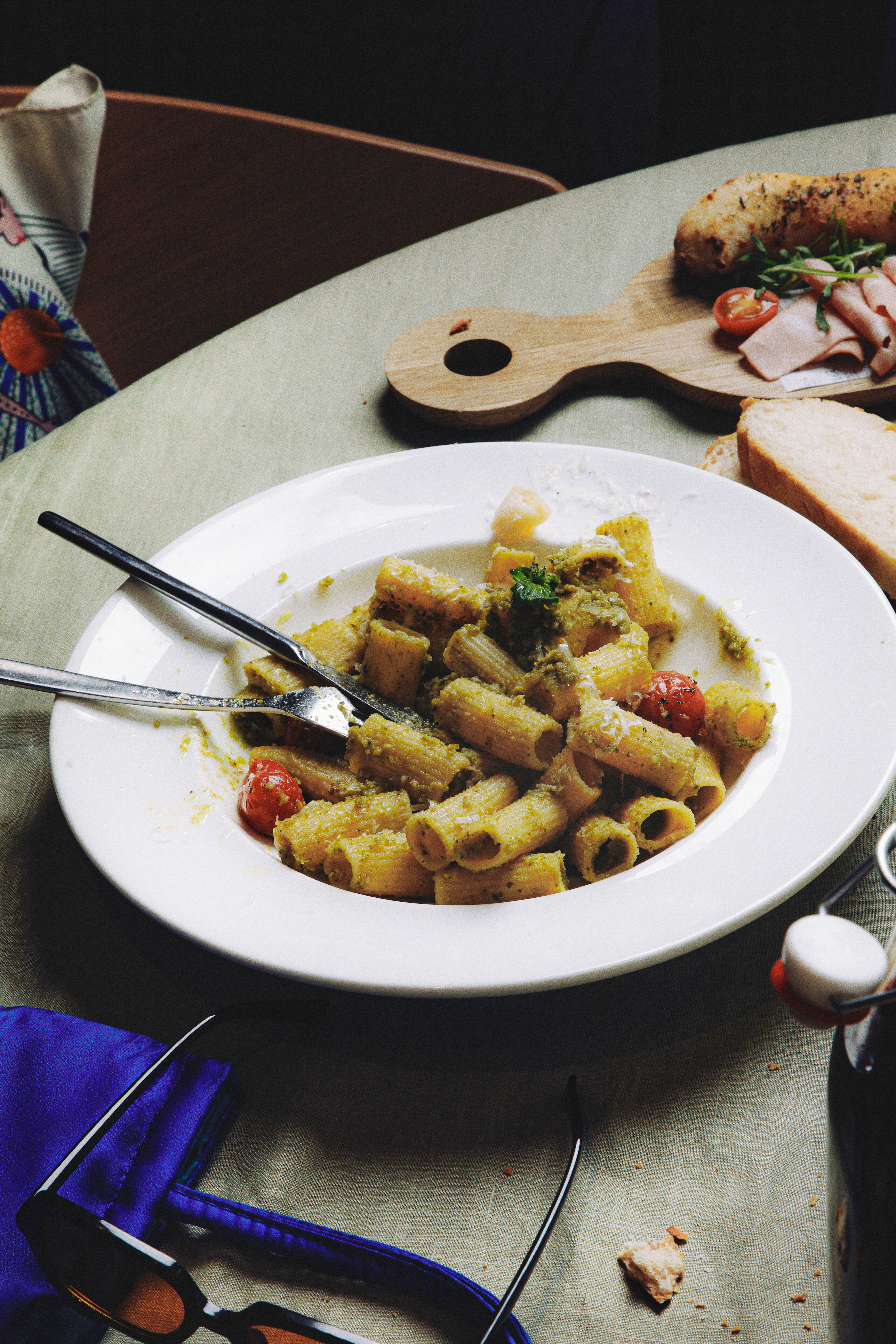 Pesto rigatoni pasta with cherry tomatoes, parmesan, bread, and ham.