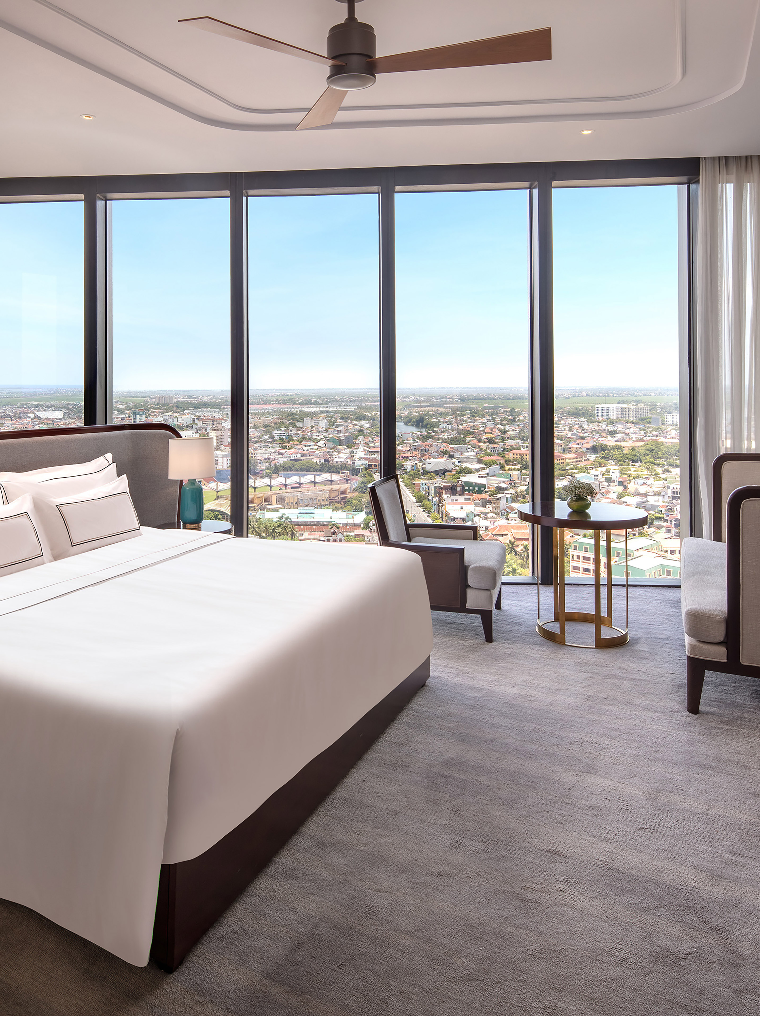 Modern luxury hotel suite bedroom with panoramic city views.