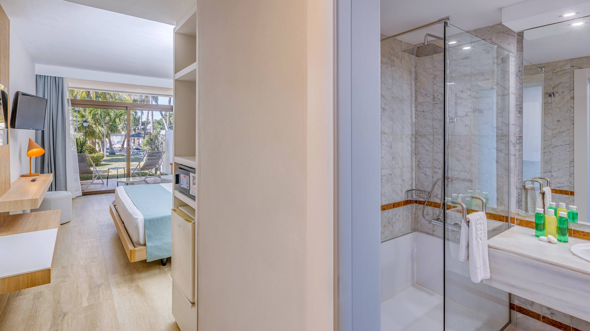 a bathroom with a glass shower and a bed