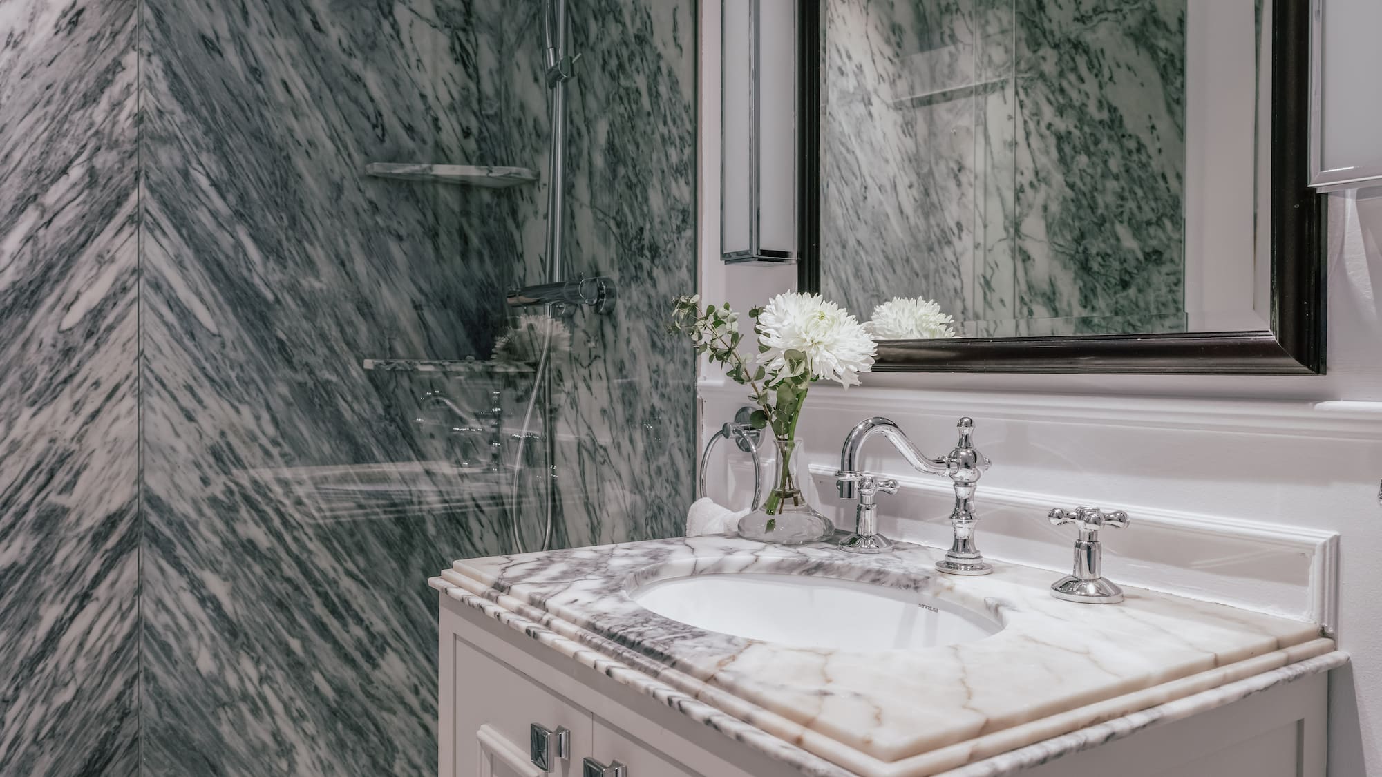 Elegant bathroom with green marble shower and white vanity.
