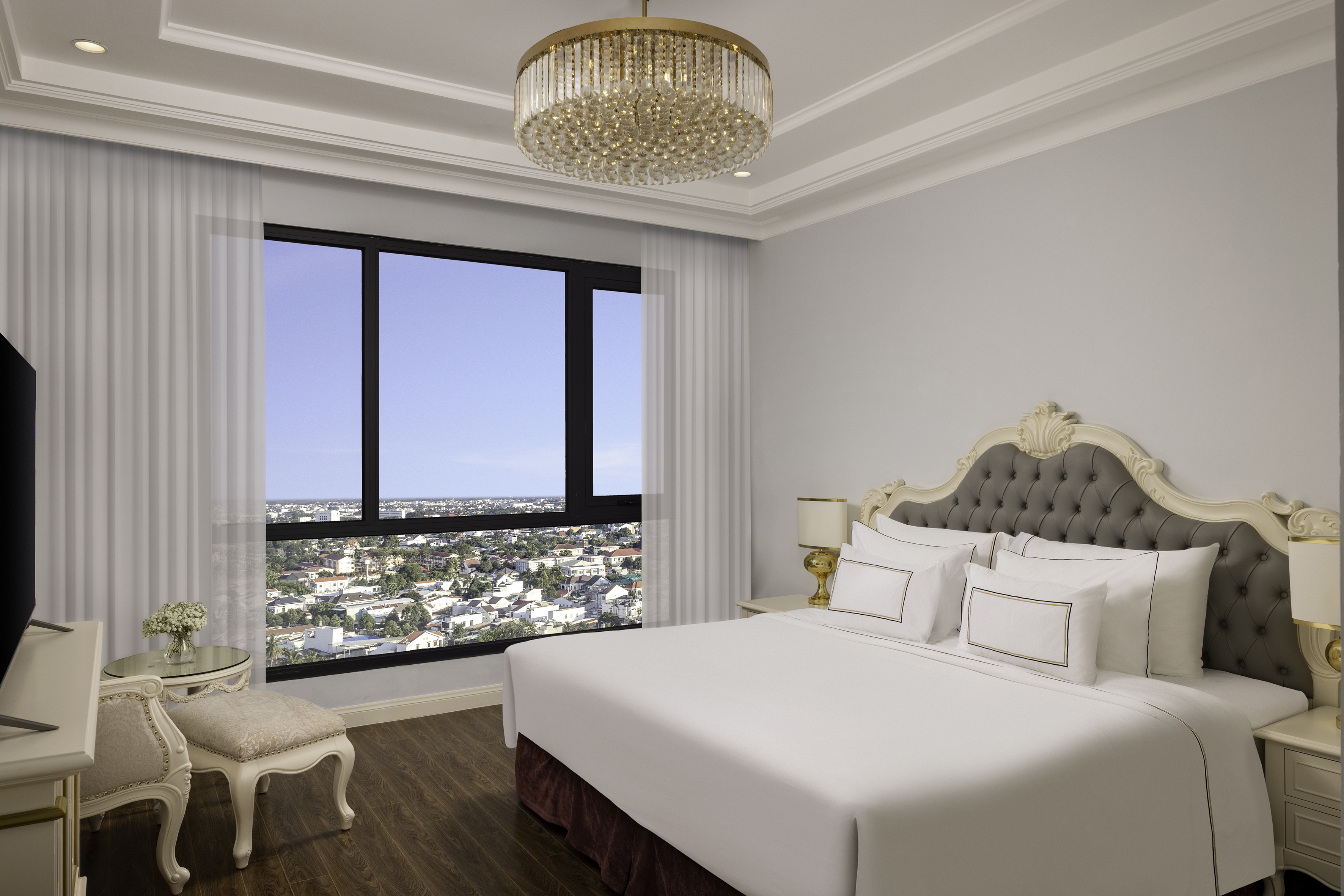 Luxury bedroom with city view, king bed, tufted headboard, and chandelier.