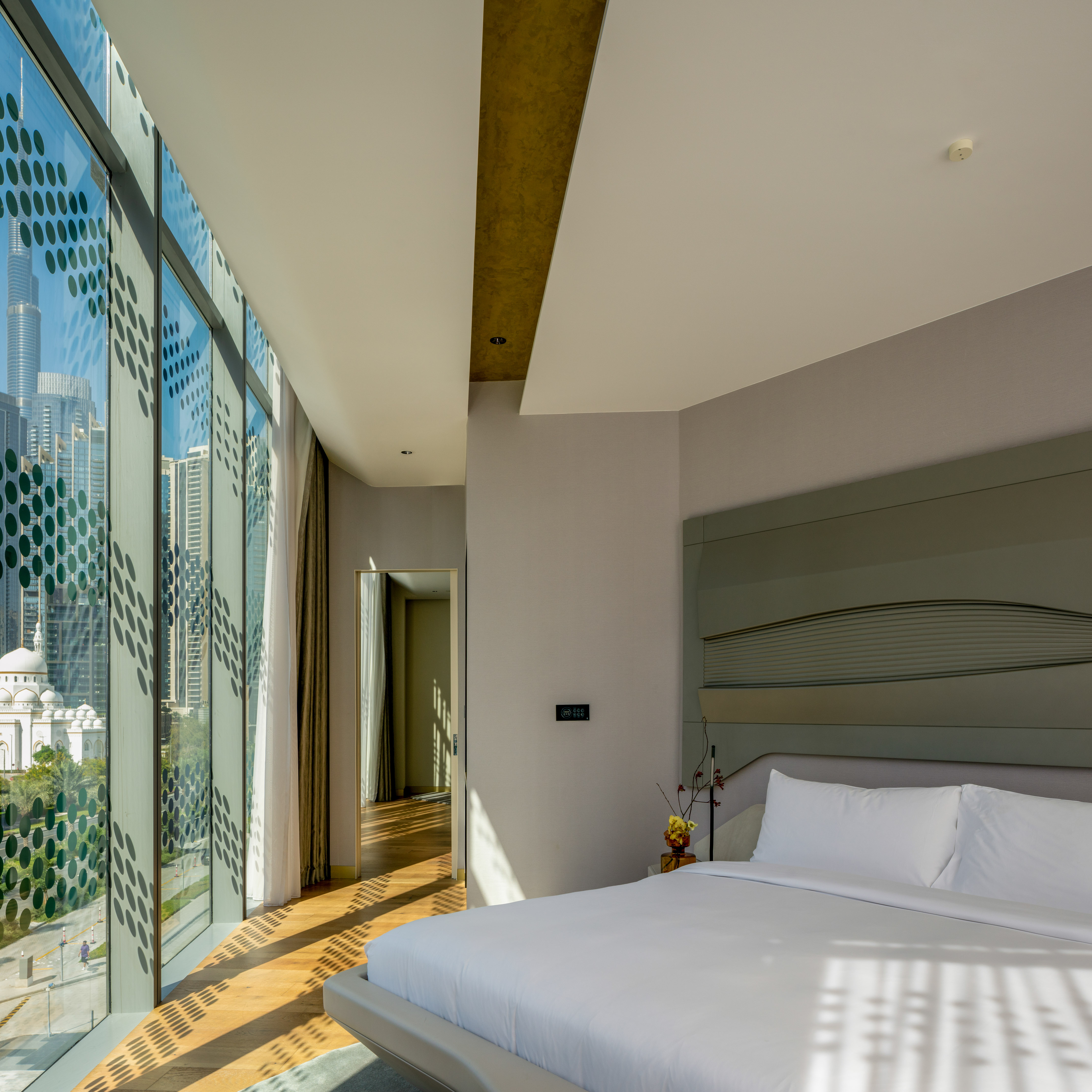 Modern bedroom with city view, Burj Khalifa visible through patterned window, Dubai.
