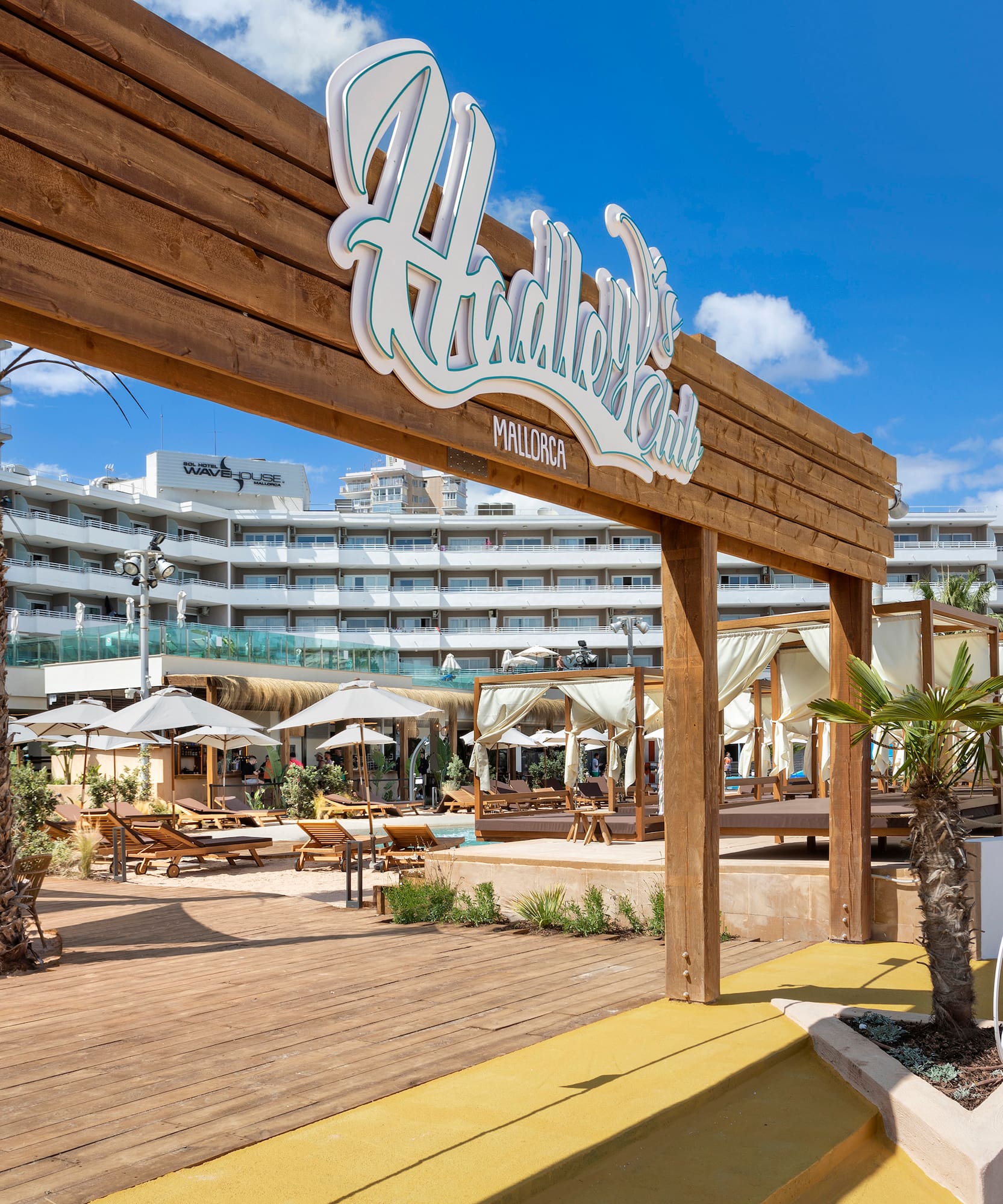 a wooden sign with palm trees and umbrellas