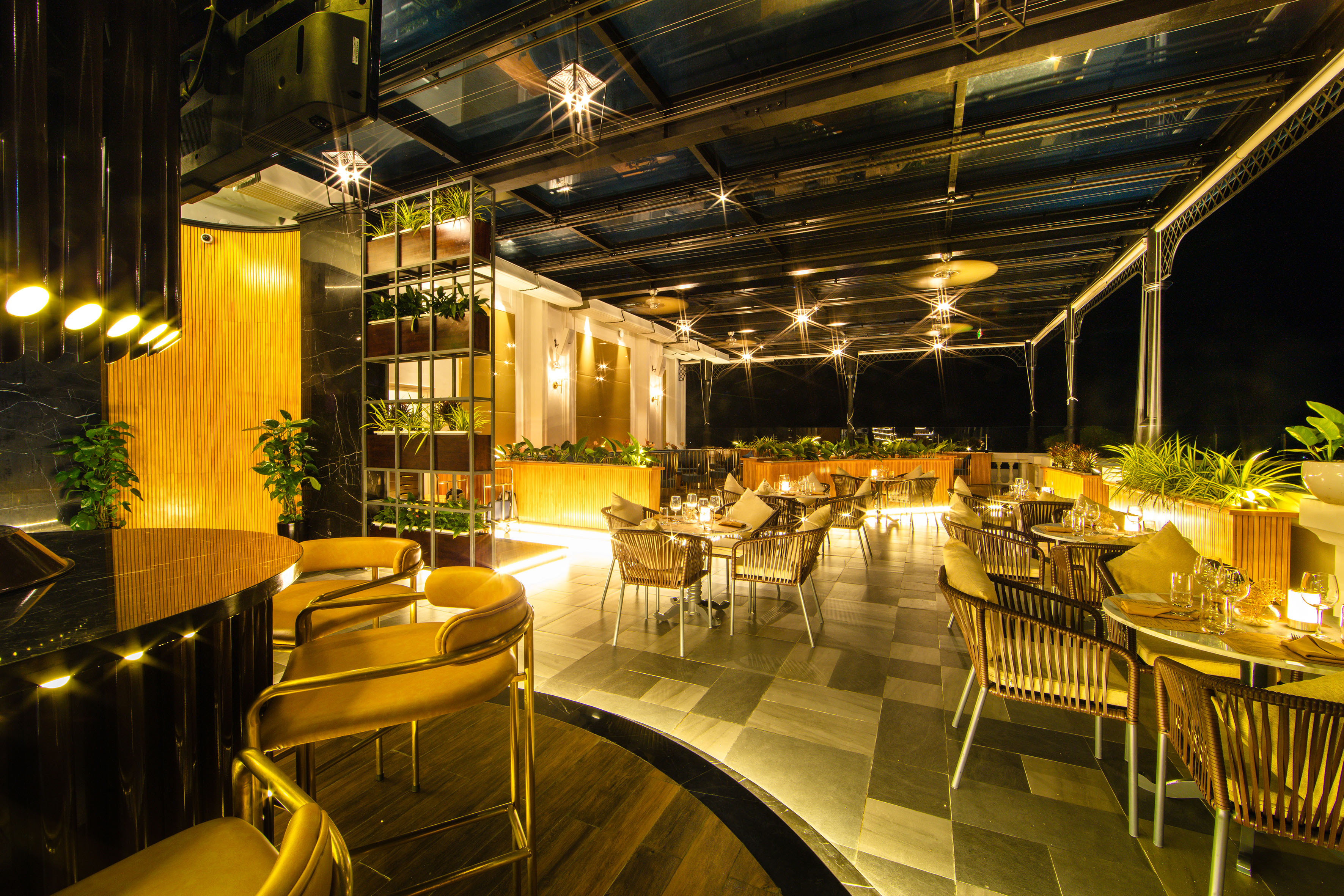 Modern rooftop restaurant & bar at night with ambient lighting and glass roof.