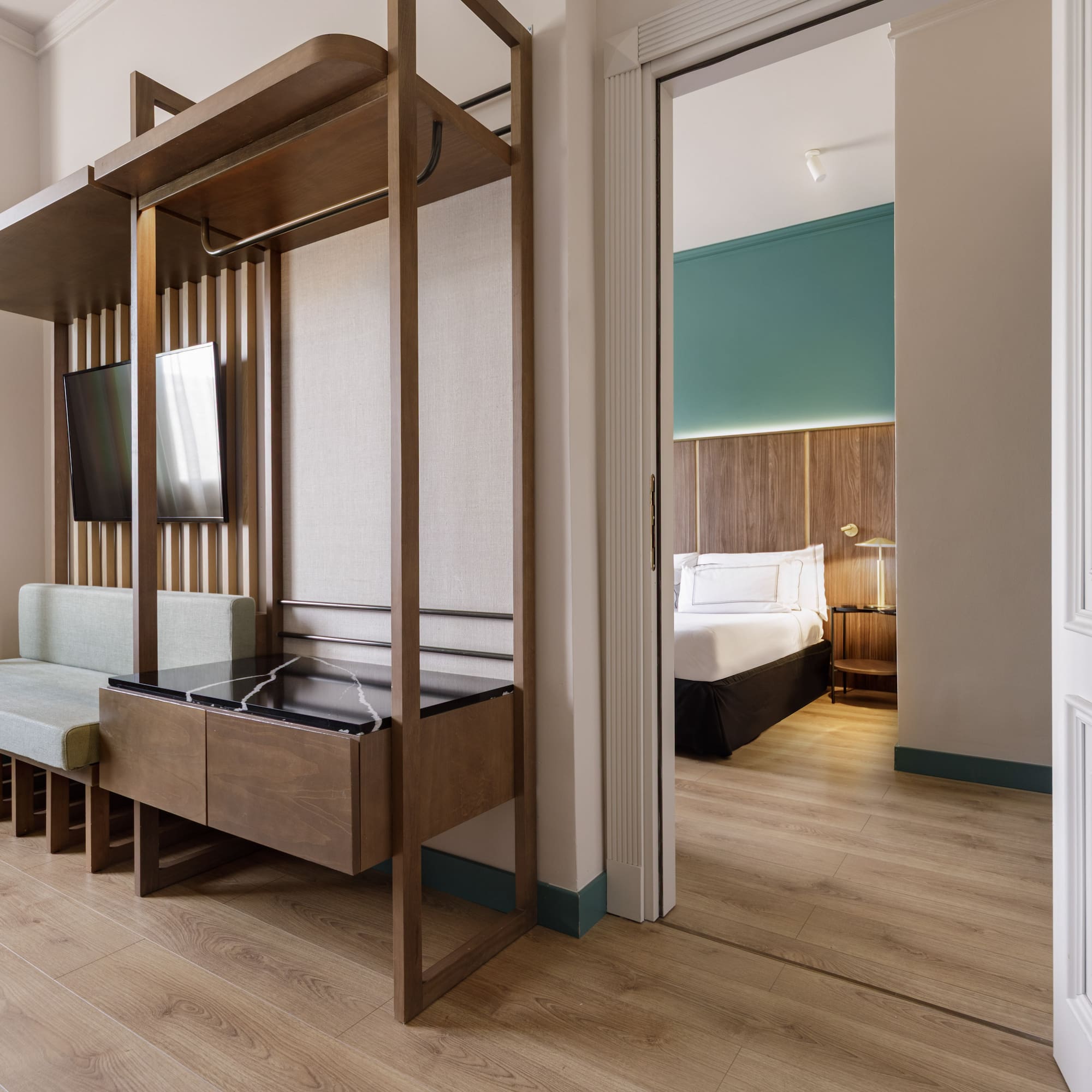 Contemporary hotel suite with wood paneling, living area, and open bedroom door.