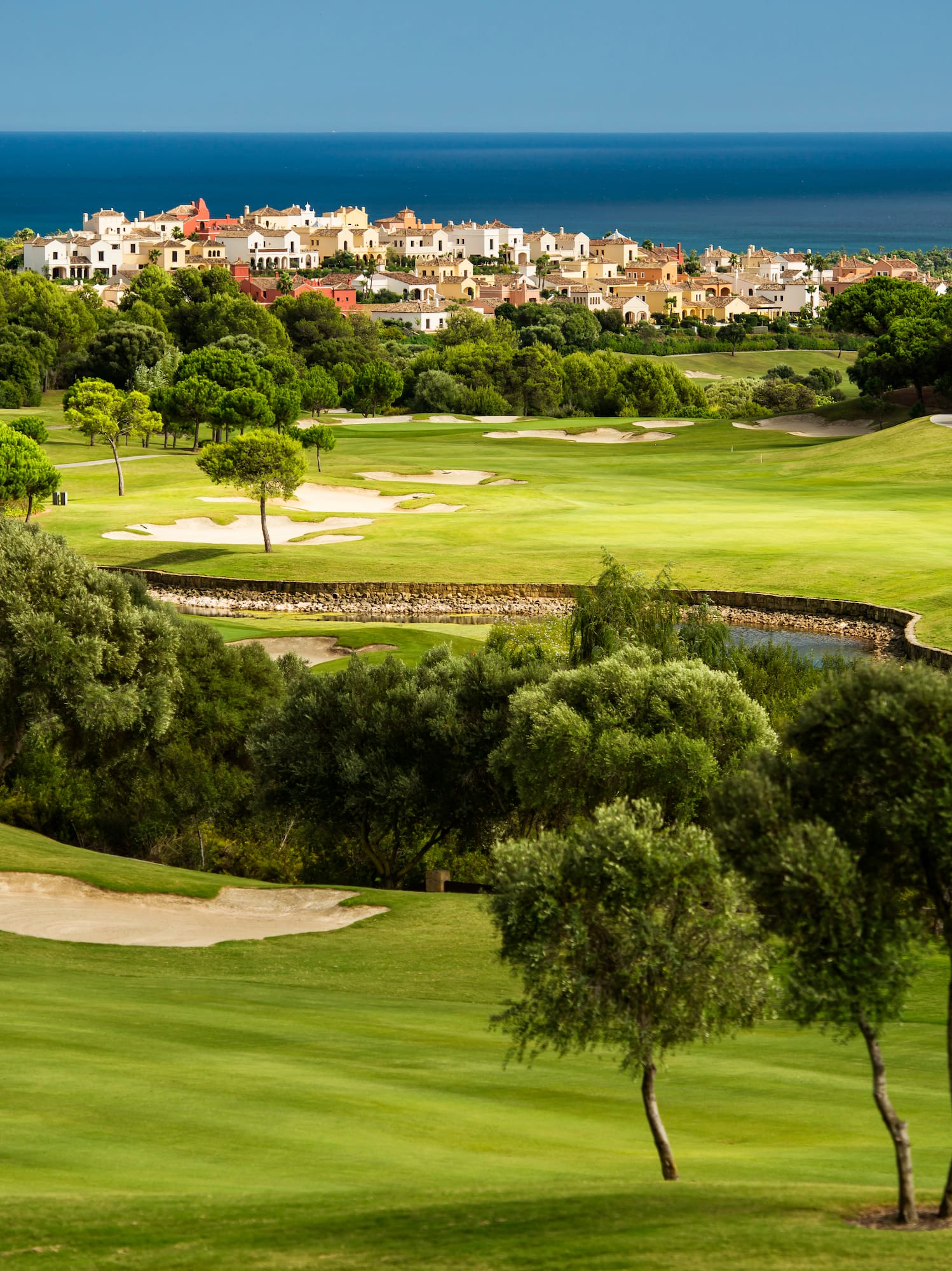 a golf course with trees and buildings in the background