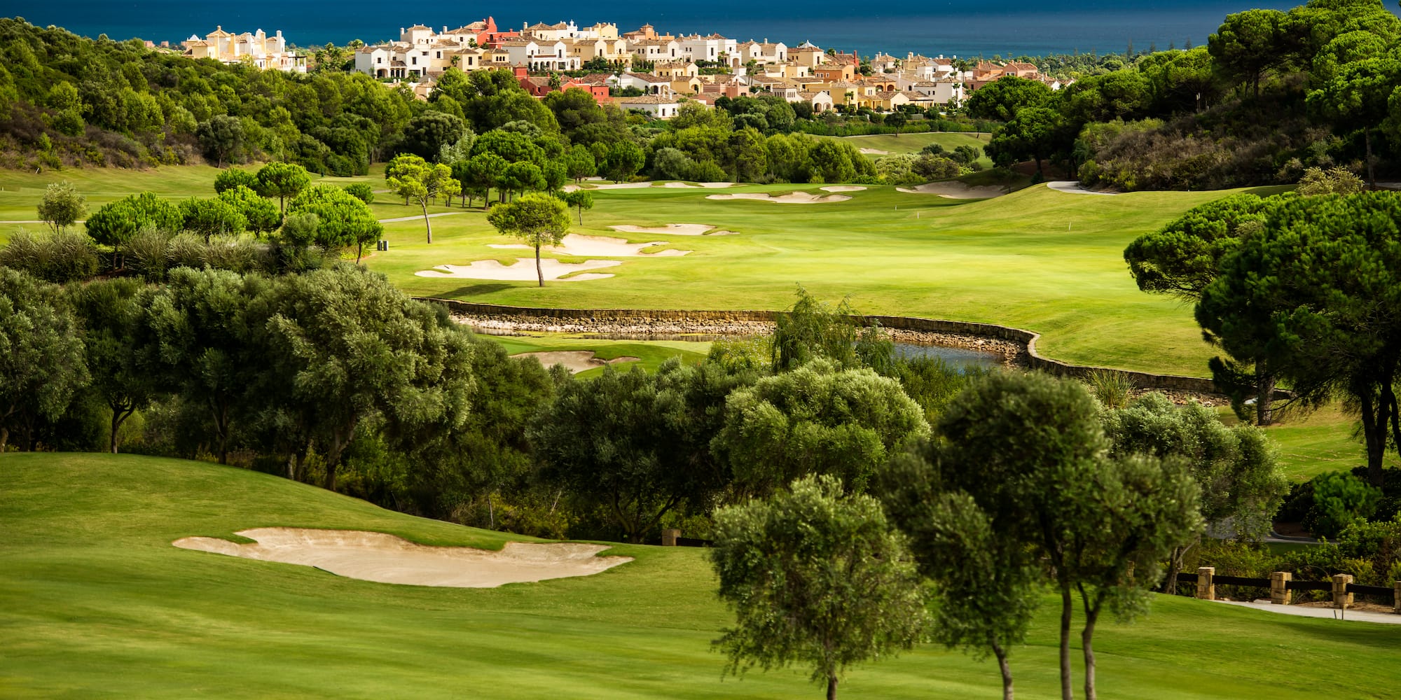 a golf course with trees and buildings in the background