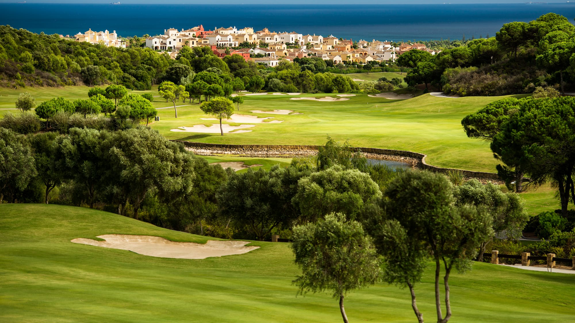a golf course with trees and buildings in the background