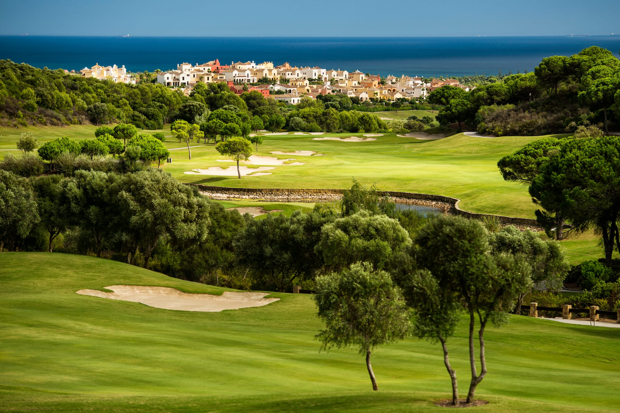 a golf course with trees and buildings in the background