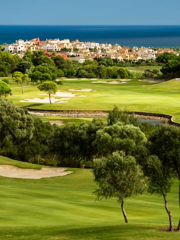 a golf course with trees and buildings in the background