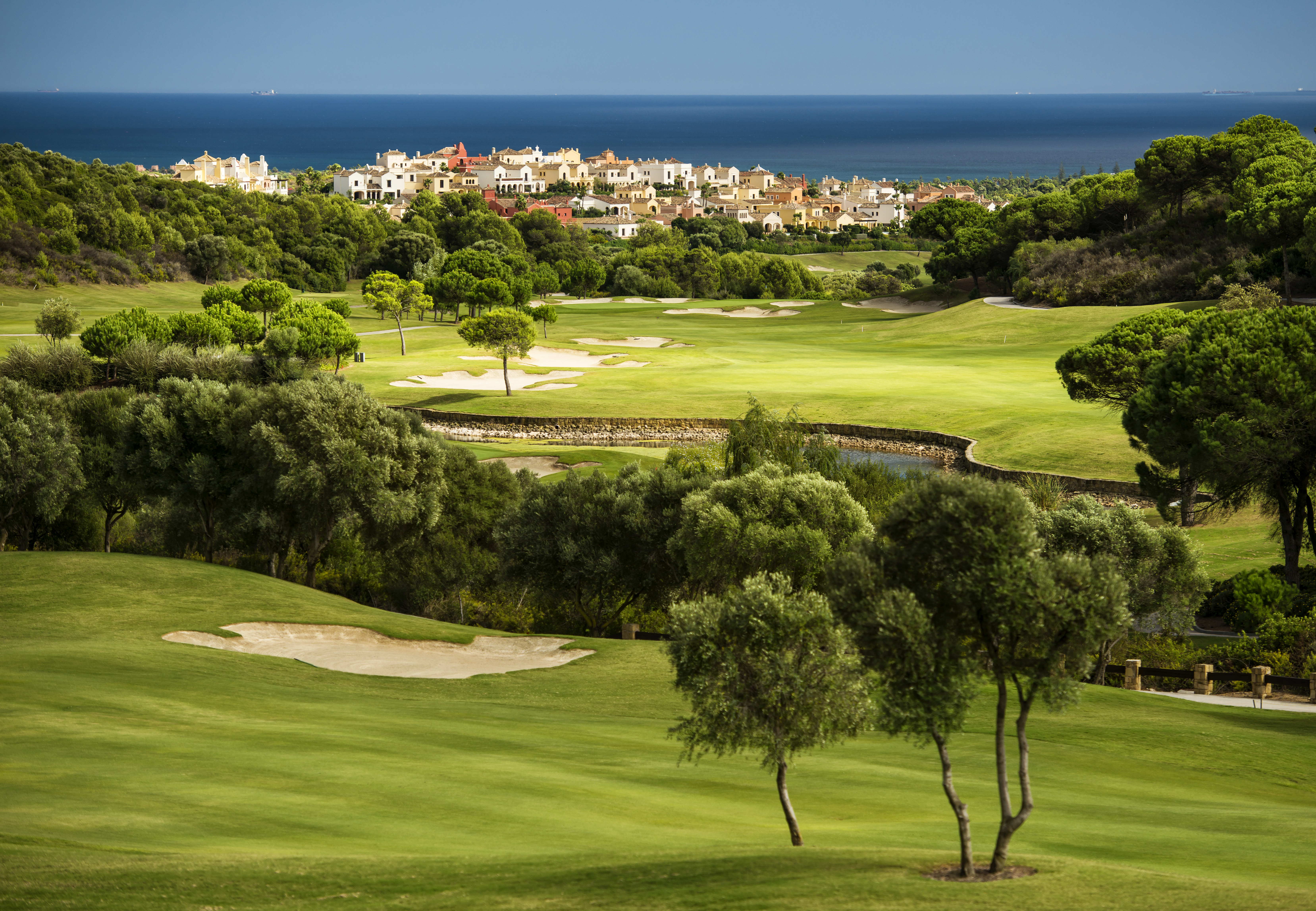 a golf course with trees and buildings in the background