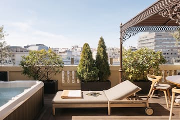 a deck with a hot tub and a lounge chair.