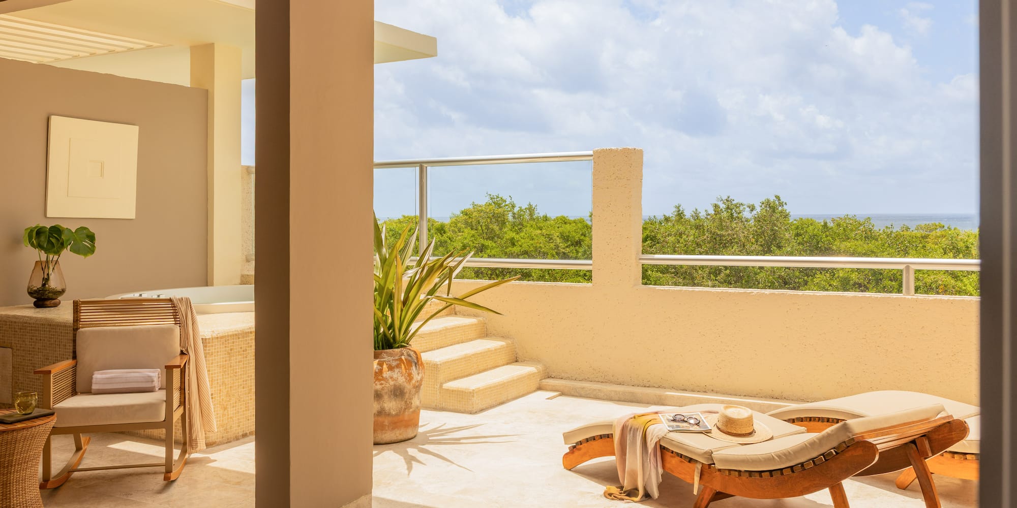 Luxury terrace with sun lounger, jacuzzi, and lush ocean view.