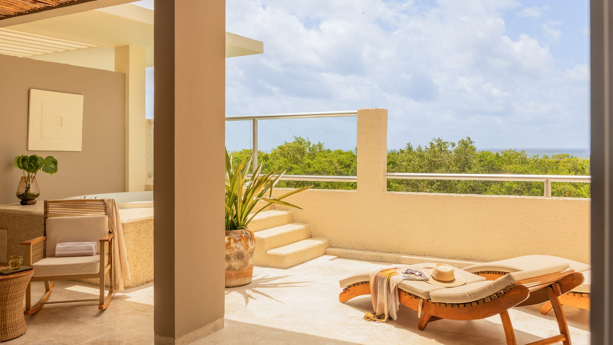 Luxury terrace with sun lounger, jacuzzi, and lush ocean view.