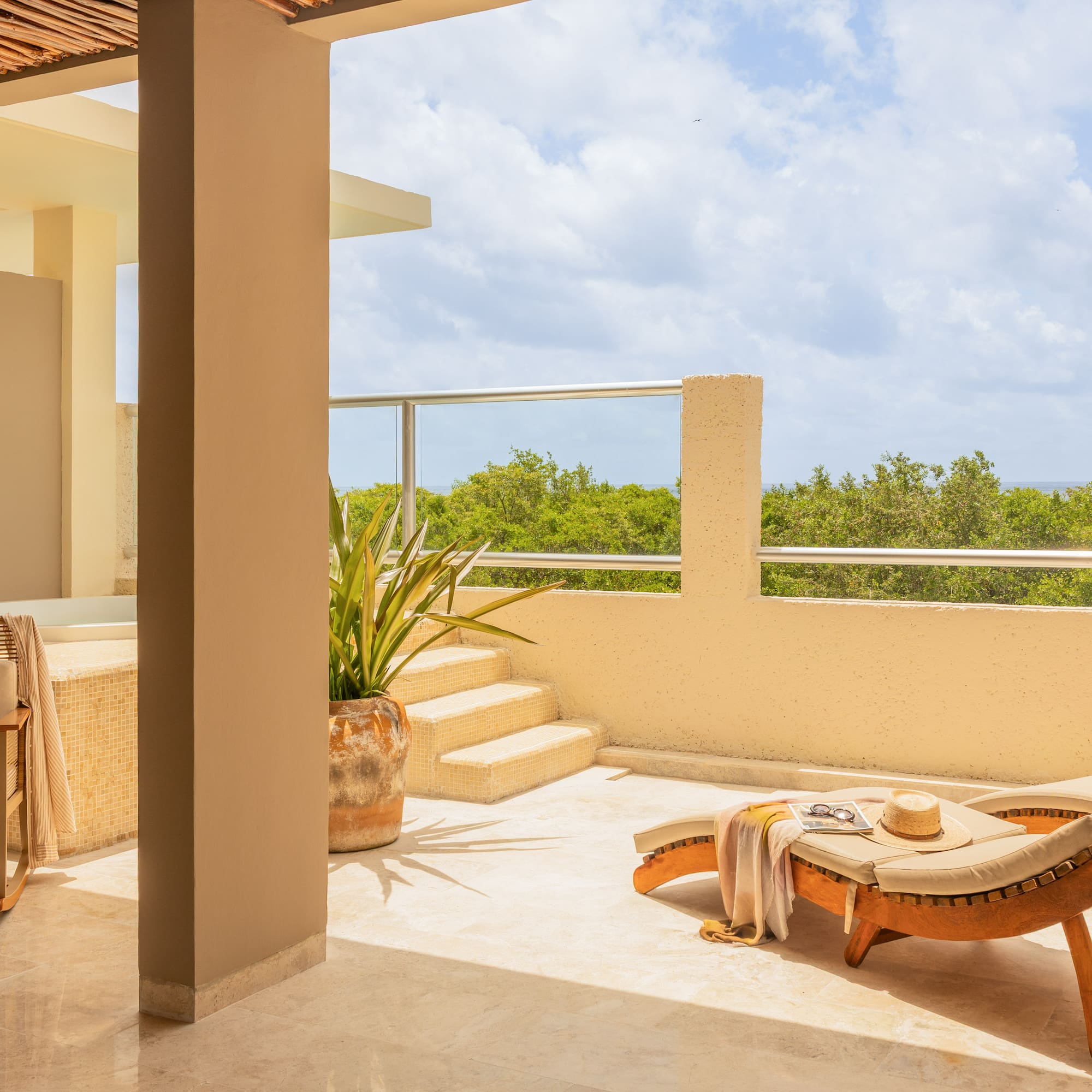 Luxury terrace with sun lounger, jacuzzi, and lush ocean view.