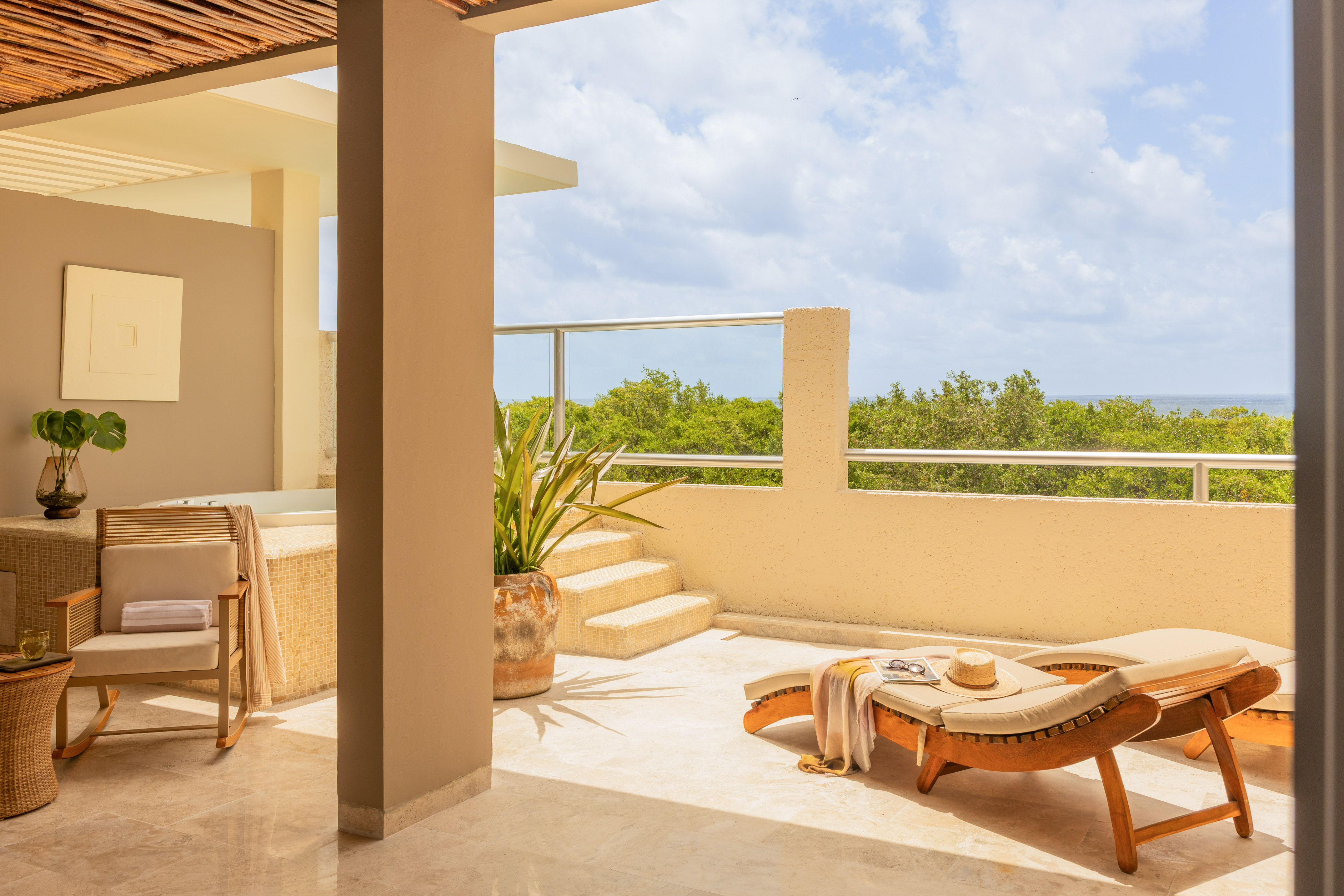 Luxury terrace with sun lounger, jacuzzi, and lush ocean view.