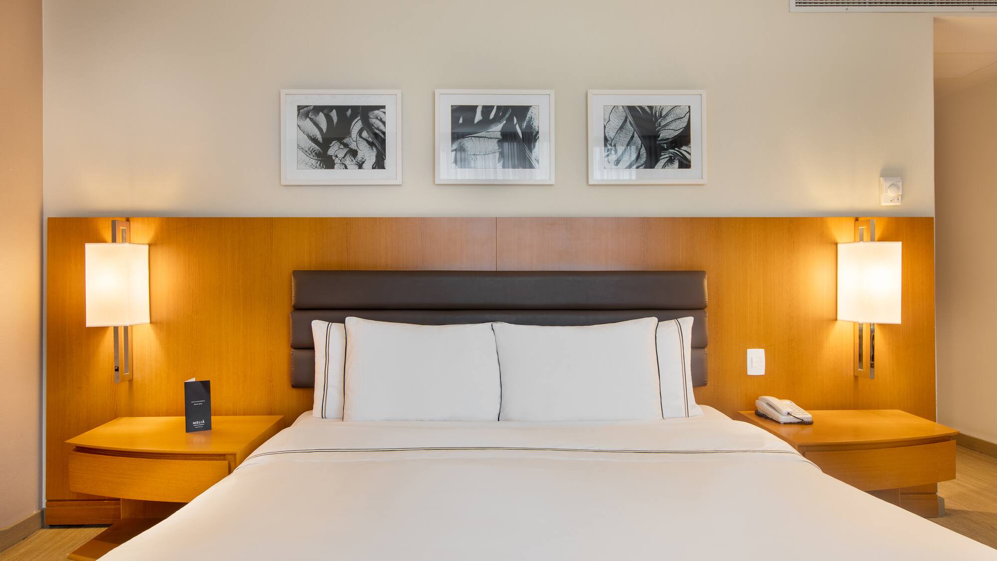 a bed with white sheets and a brown headboard