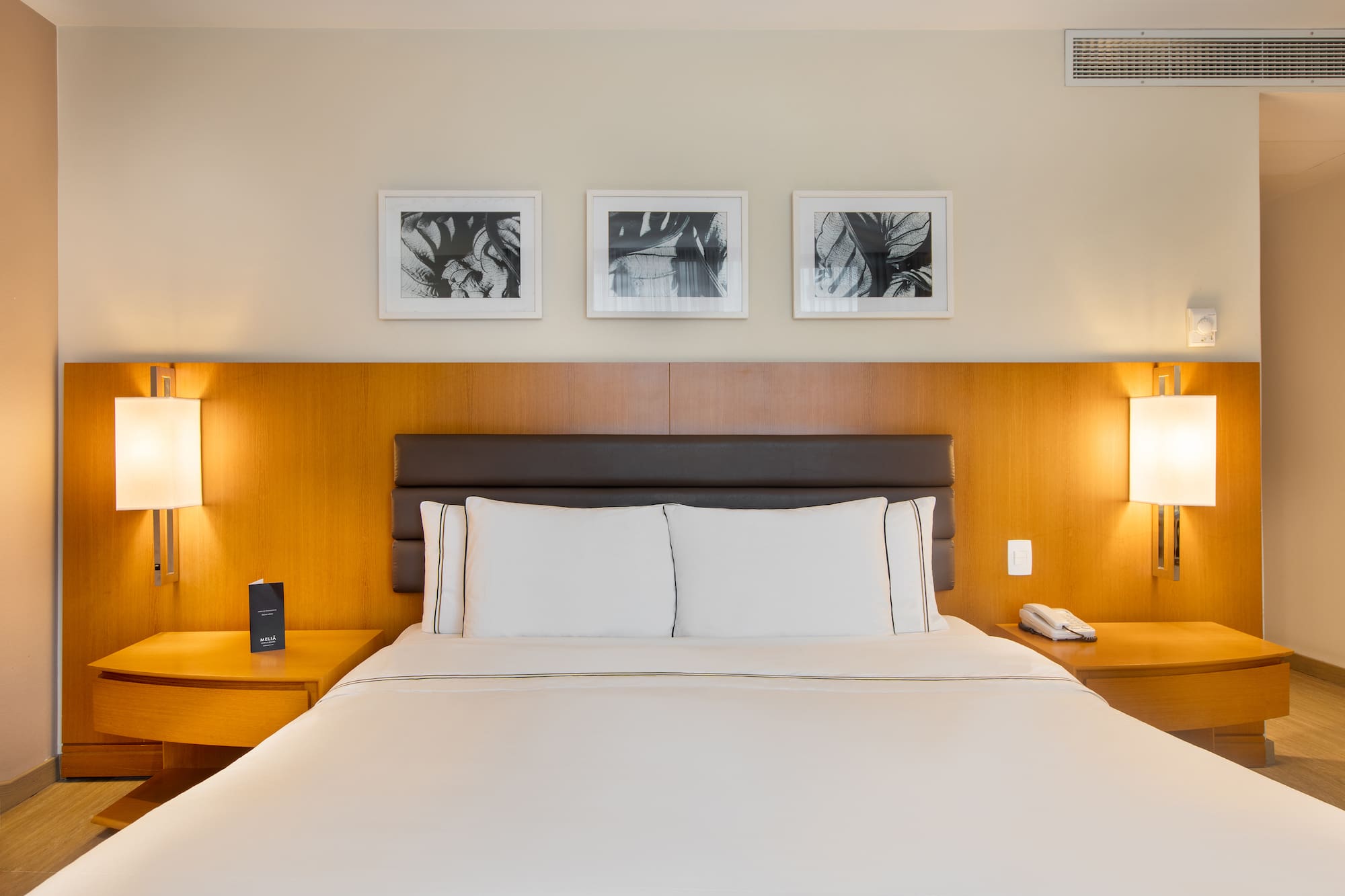 a bed with white sheets and a brown headboard