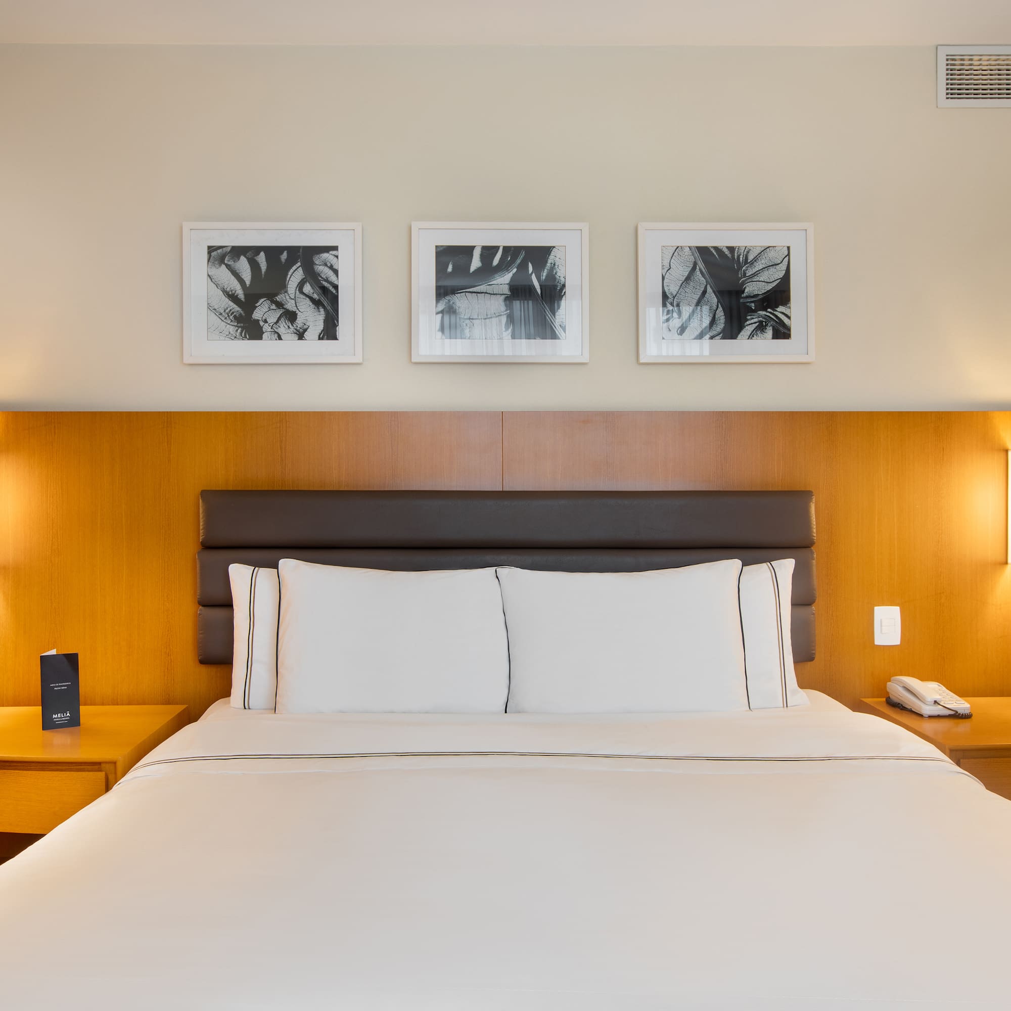 a bed with white sheets and a brown headboard