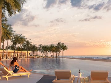 a woman sitting on a lounge chair next to a pool