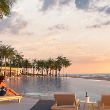 a woman sitting on a lounge chair next to a pool