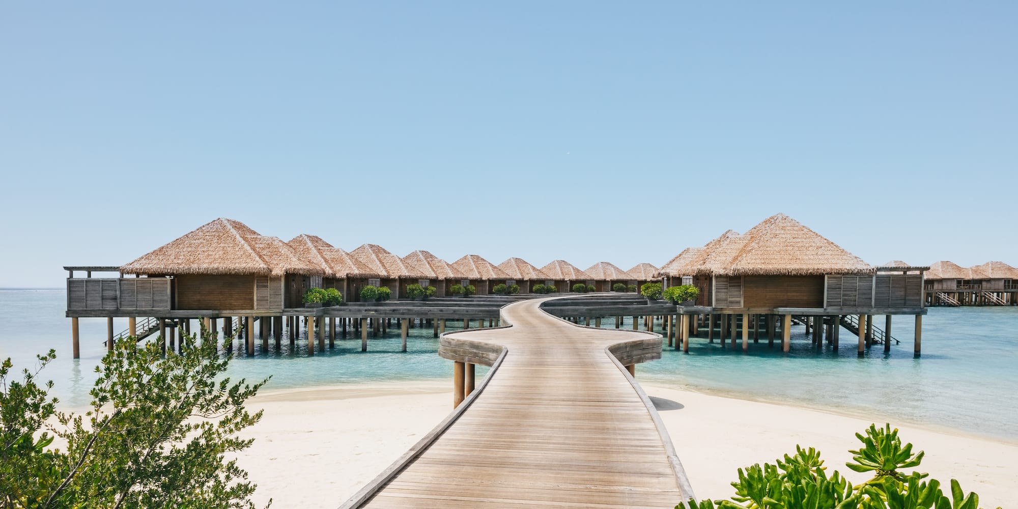 a walkway leading to a beach with huts on stilts