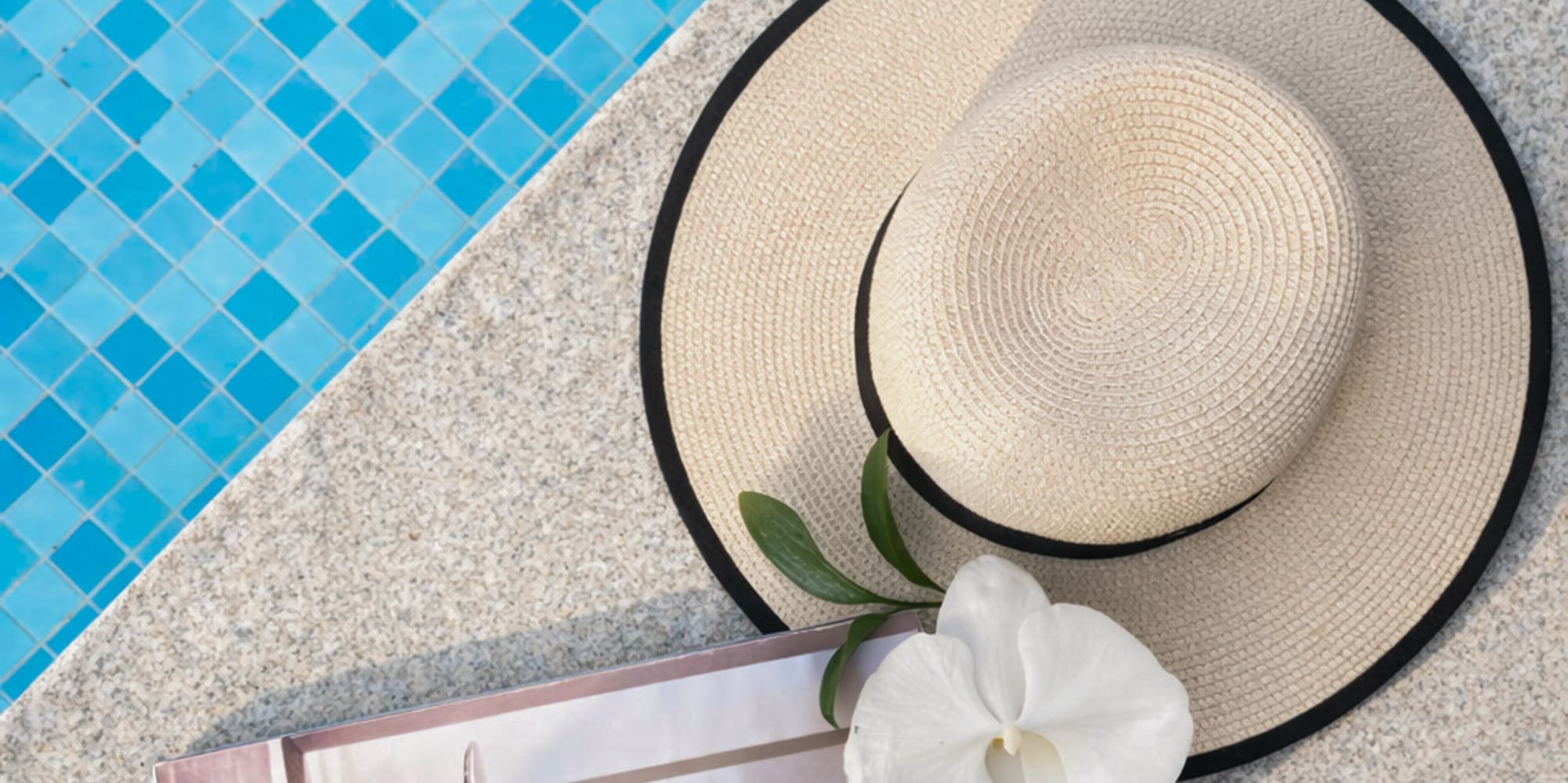 a hat and a book next to a pool