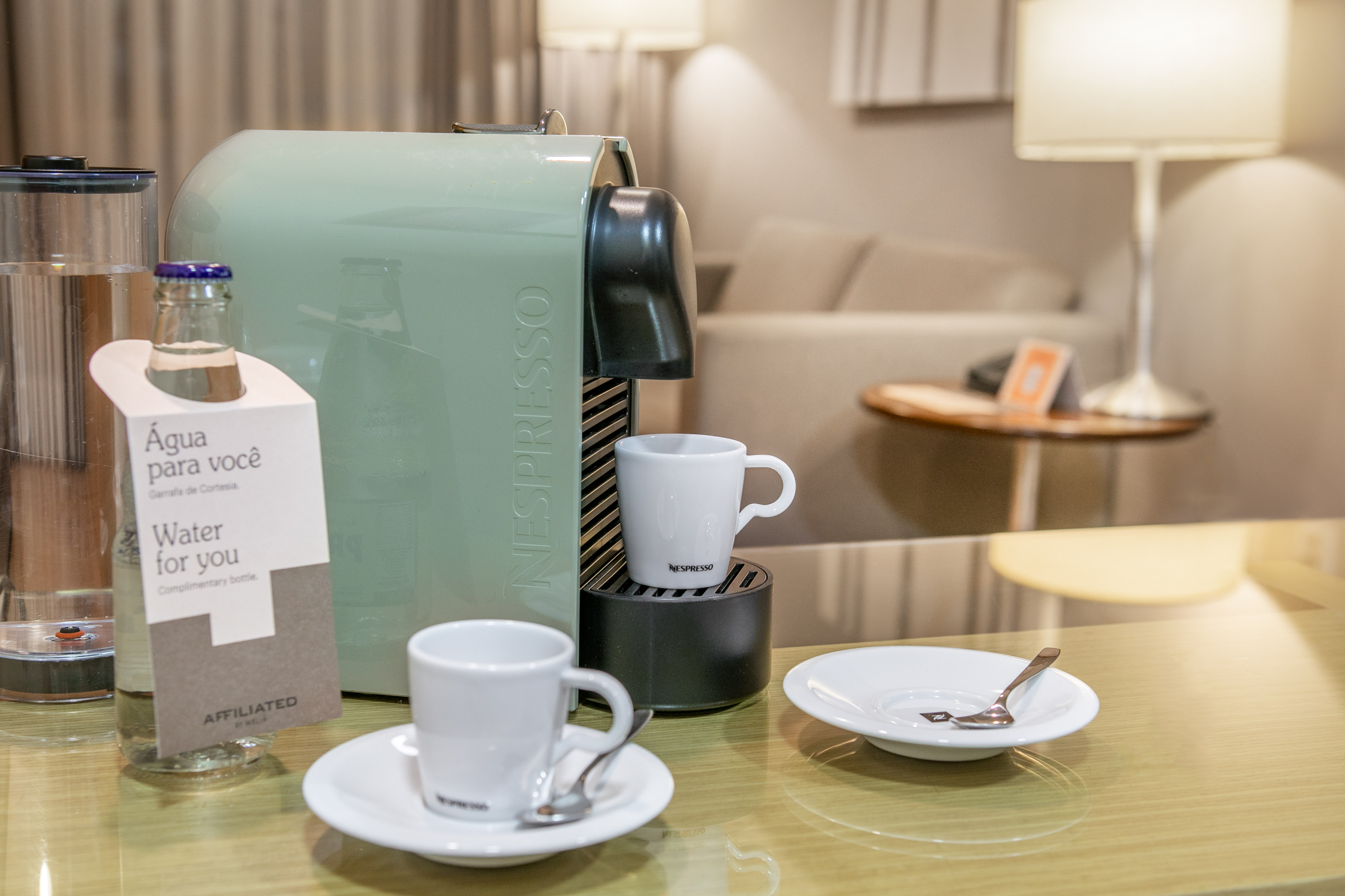 Nespresso coffee machine with cups and complimentary water in hotel room.
