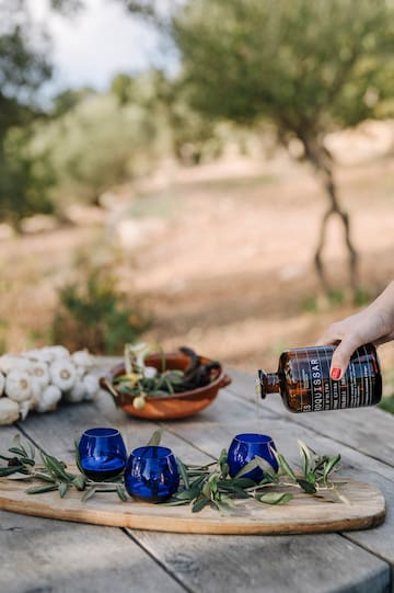 a person pouring a bottle into blue cups