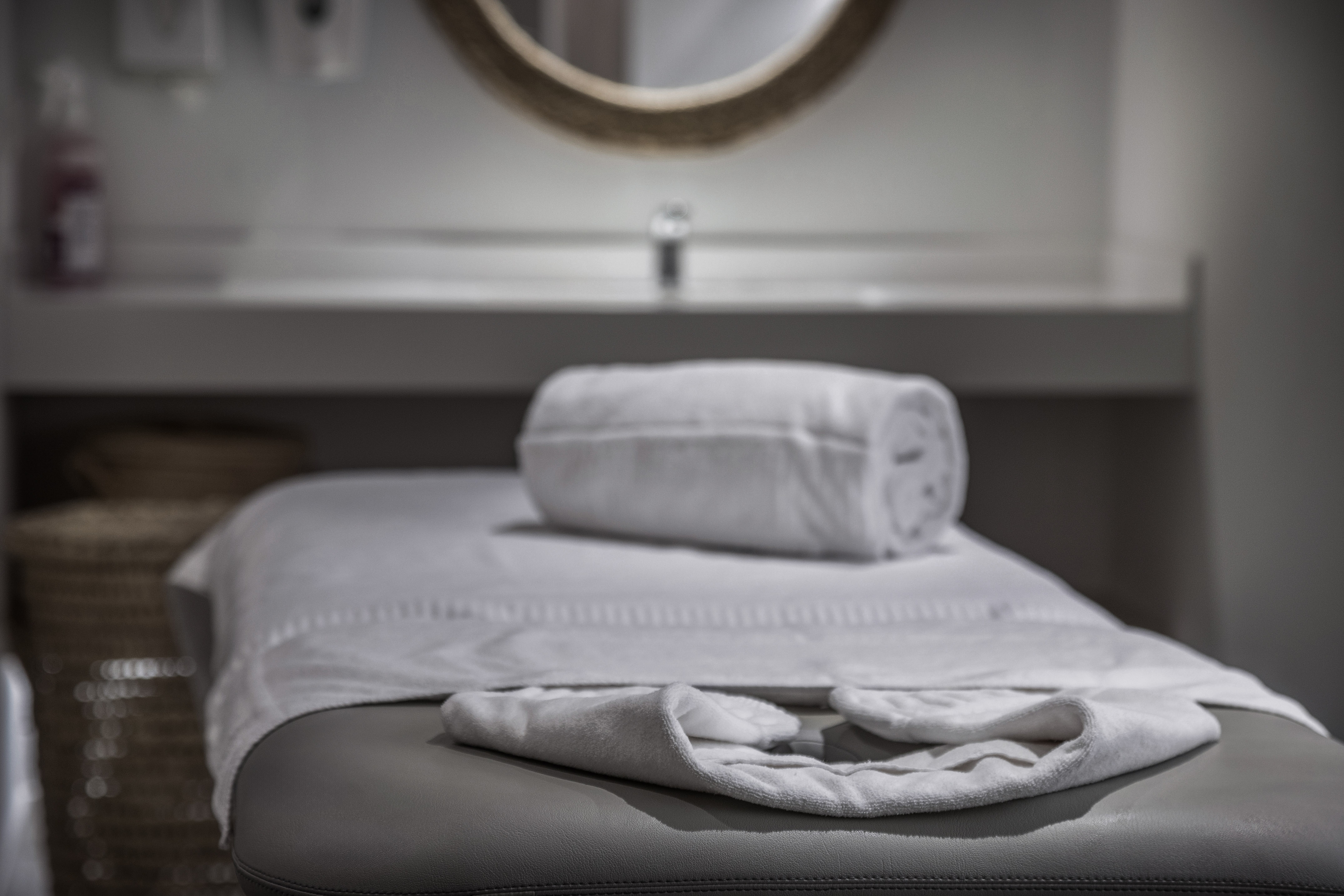 Clean white towels on a spa massage table in a tranquil treatment room.