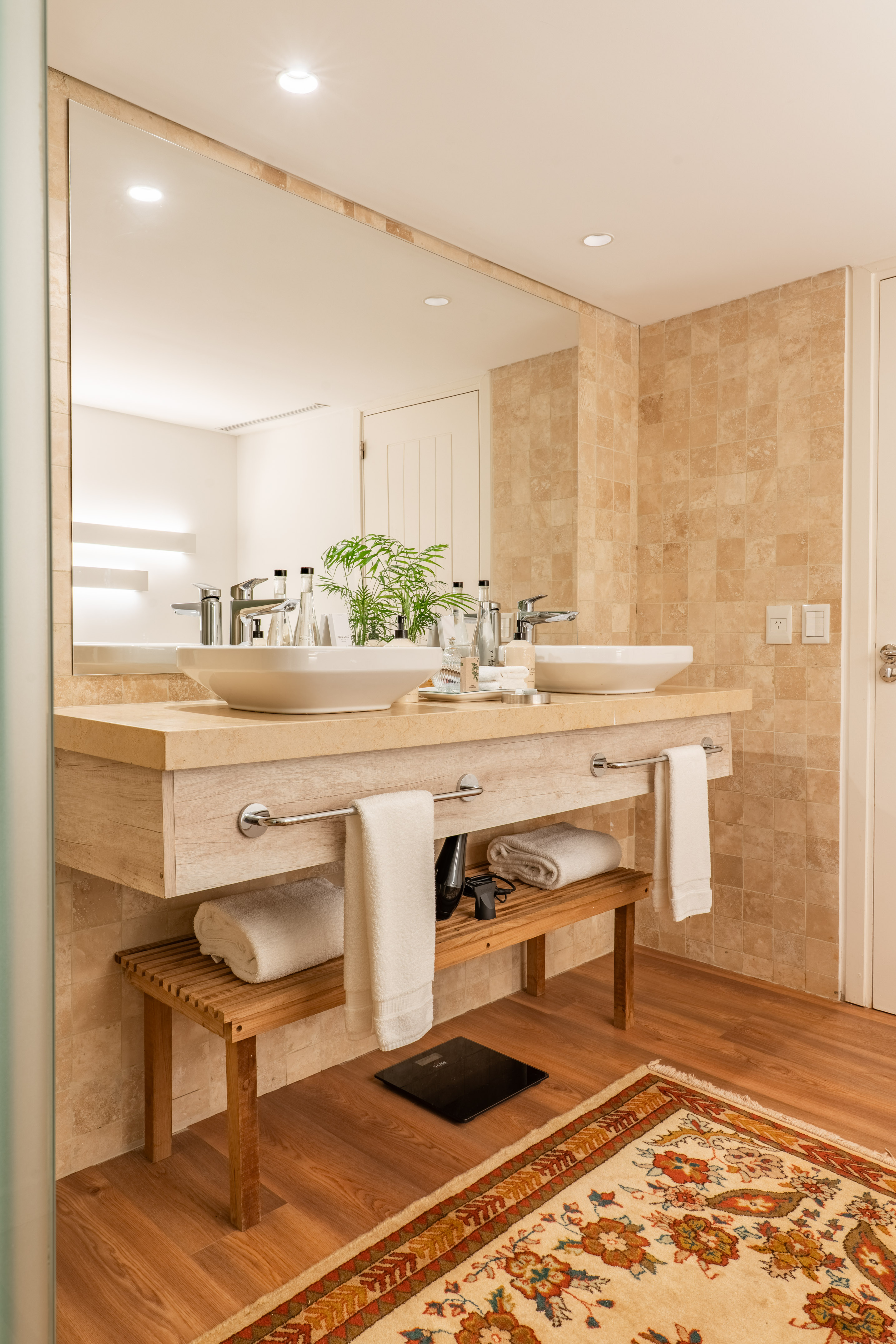Modern double vanity bathroom with stone counter, large mirror, and wood accents.