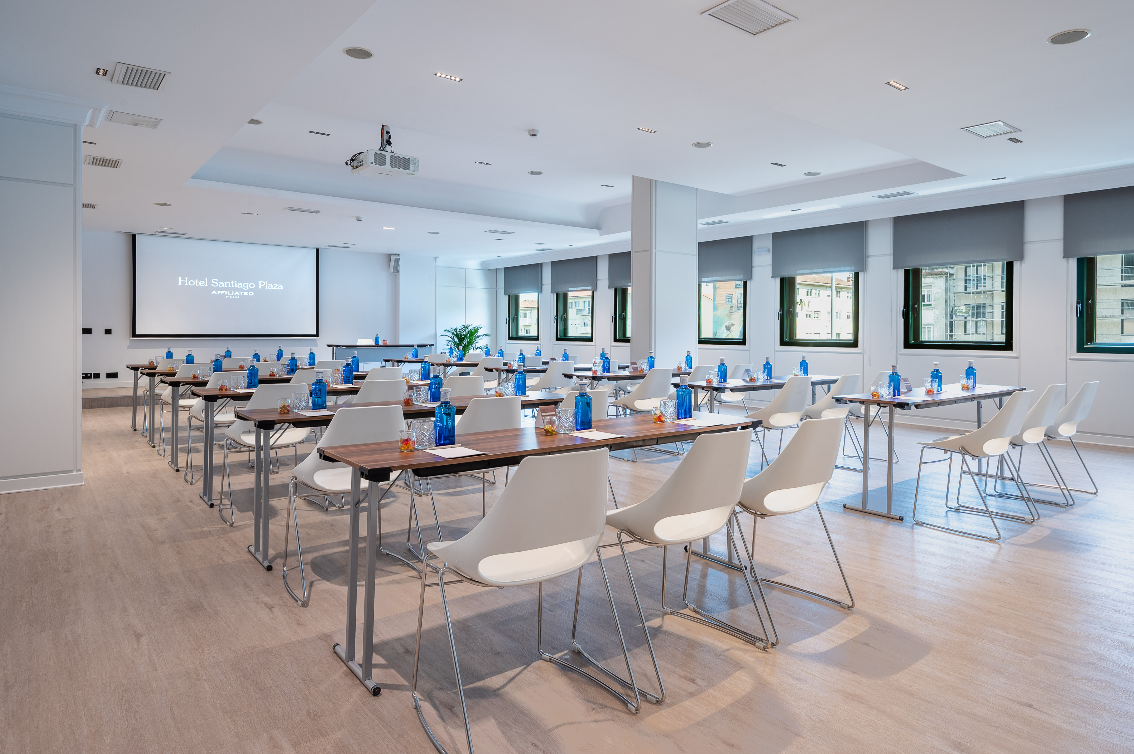 Hotel Santiago Plaza meeting room with projector, tables, chairs, and water bottles.